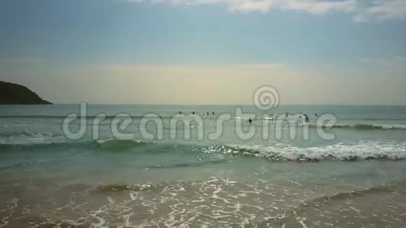 海浪细软的沙滩和远处的冲浪者视频的预览图