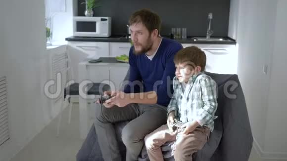家庭娱乐爸爸带着儿子带着游戏控制器在度假的房间里玩视频的预览图