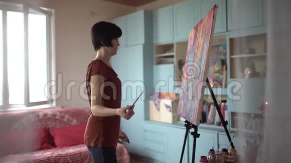 女艺术家在艺术工作室画一幅抽象画侧视4千克视频的预览图