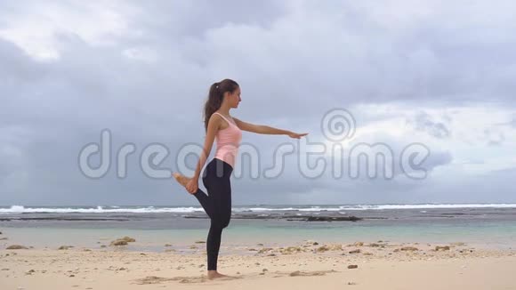 做瑜伽练习的女人在巴厘岛的海洋海岸上进行女孩训练和鞠躬姿势视频的预览图
