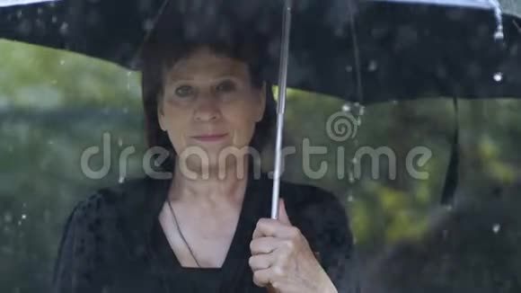 一个穿黑衣服的女人在雨中打伞视频的预览图