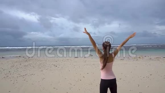 穿着运动服的女人举起双手在沙滩上视频的预览图