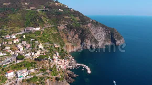 从Riomaggiore村的远处鸟瞰悬崖边上的房子有船的海湾葡萄和橄榄种植园视频的预览图