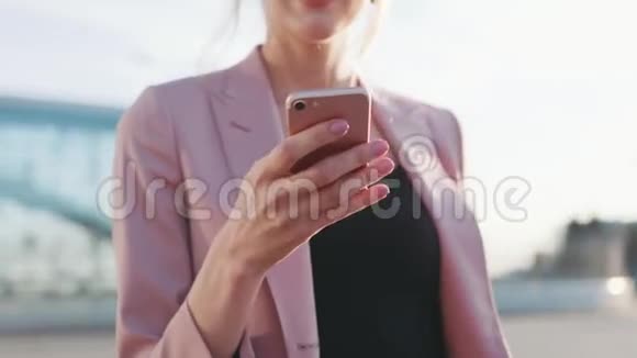 近距离观看一只小小的雌性手用手机发短信外拍摄天气晴朗时髦的样子微笑视频的预览图