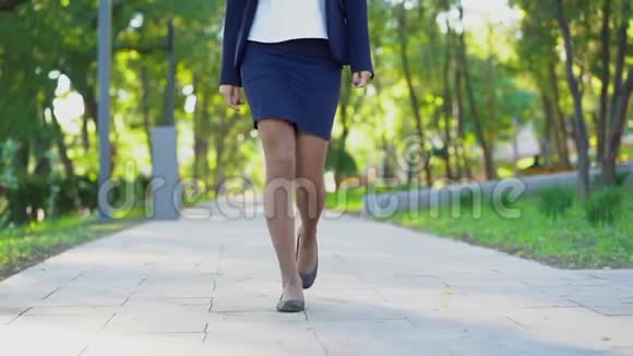 一个穿着正式服装的年轻商务女性的腿在绿色公园里独自行走女孩总是工作或者视频的预览图