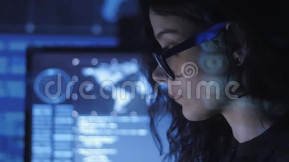 戴眼镜的年轻女性程序员在数据中心的一台电脑上工作的画像上面摆满了显示屏视频的预览图