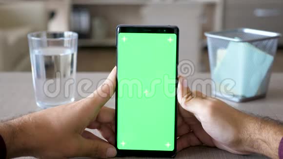 男性手握一部带有绿色屏幕色度模拟的智能手机视频的预览图