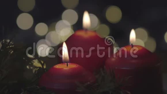 三支红色的圣诞蜡烛在闪烁的灯光模糊的背景上燃烧视频的预览图