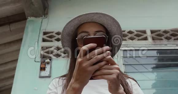 时尚女性在破旧建筑附近使用智能手机视频的预览图
