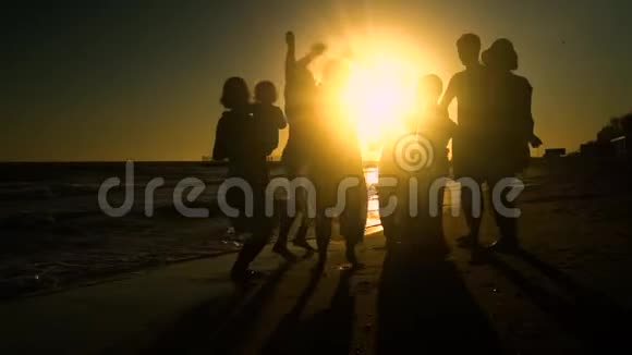 欢乐的人群在海滩上跳舞他们在阳光下跳跃人们玩得很开心他们很开心人的剪影视频的预览图