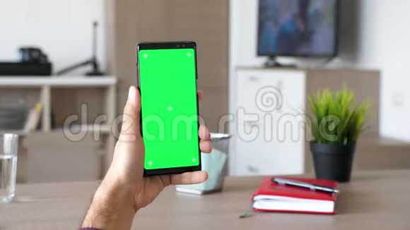 男人手里拿着一部现代智能手机上面有绿色屏幕的色度模型视频的预览图