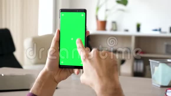 男人的手在现代智能手机上上下滚动绿色屏幕色度模拟视频的预览图