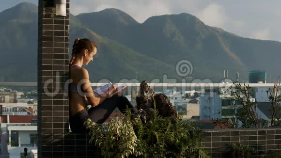 女孩坐在盆栽的露台墙上打电话视频的预览图