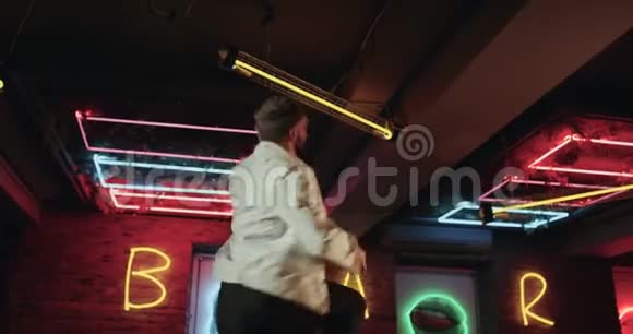 精力充沛的年轻人带着胡须在酒吧里跳舞背景上有令人惊叹的灯光视频的预览图