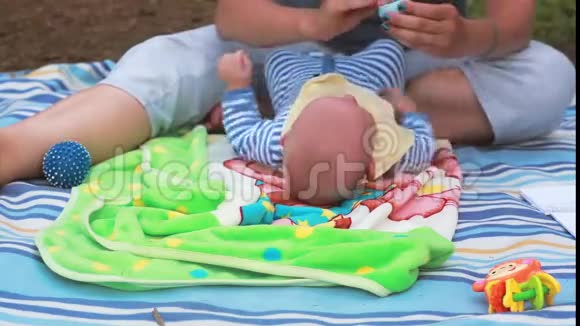 女人在婴儿脸上涂一些奶油活泼的婴儿躺在毯子上摇着手臂玩具到处都是视频的预览图