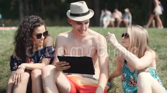 朋友们在海滩上看着他们的平板电脑视频的预览图