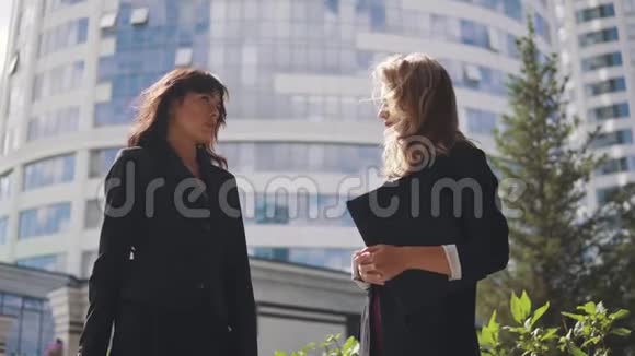 商业中心背景上的商人剪影两个商务女性面对面地在户外交谈视频的预览图