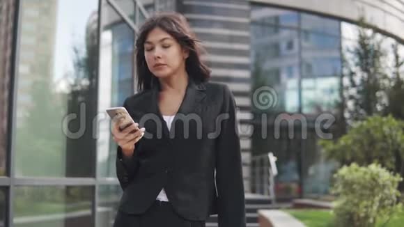 漂亮的年轻女人穿着西装用智能手机商务女性在手机上发短信视频的预览图