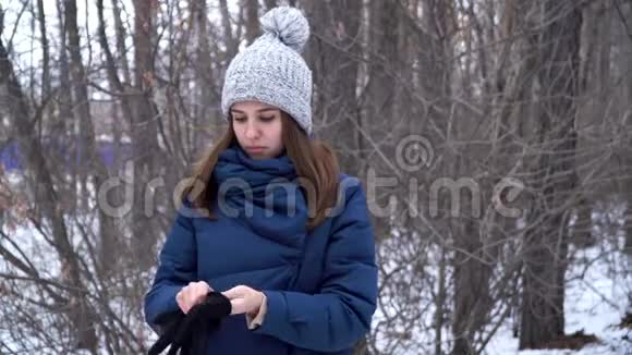 美丽的女孩站在冬天的森林里戴着手套雪白的树枝背景冬季森林景观视频的预览图