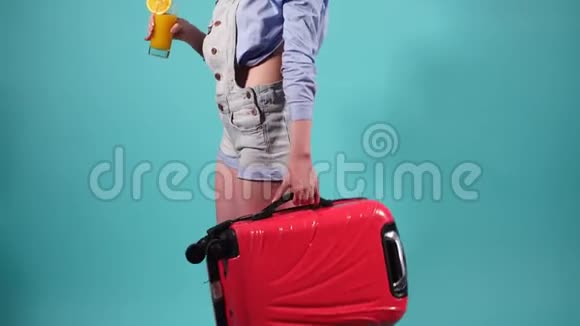 漂亮的女孩拿着一个红色的手提箱喝橙汁女孩在旅途中飞翔视频的预览图