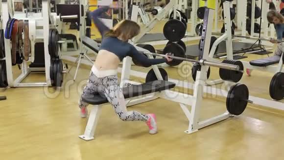 运动的女孩在健身房里用一个仰卧位的酒吧做运动视频的预览图