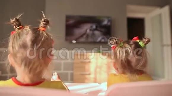 两个小妹妹在桌子上吃饭在电视上看动画片玩得很开心后景视频的预览图