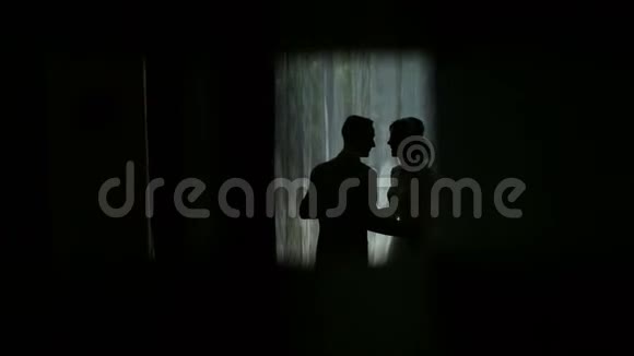 新娘和新郎靠近一扇明亮的窗户结婚纪念日剪影视频的预览图