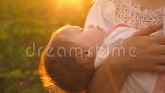 在夕阳的金色光芒中婴儿在母亲的怀里睡着了慢动作视频的预览图