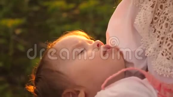 婴儿在夕阳的金色光芒中睡在母亲的怀里慢动作视频的预览图