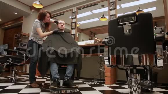 理发店里的一位女理发师把顾客男人放在椅子上开始理发视频的预览图