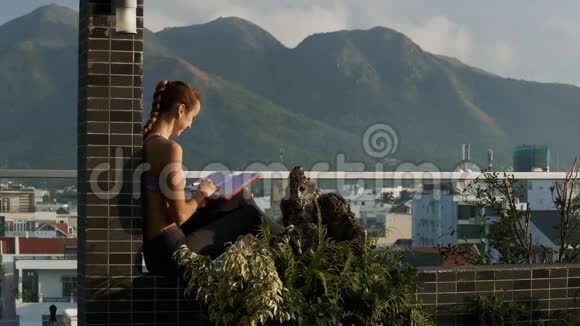 女人倚在露台上喝着咖啡拿着日记视频的预览图