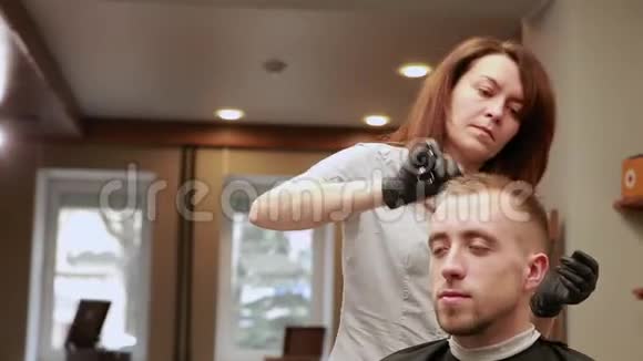 理发店里的一位女理发师把顾客男人放在椅子上开始理发视频的预览图