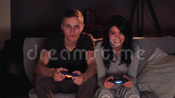 两个人在游戏机上玩视频游戏坐在家里的沙发上女孩赢了视频的预览图