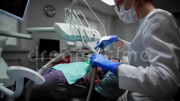 一个女人拿着一个牙医在牙医办公室里钻孔病人的牙齿并用栅栏把牙齿的残余物围起来视频的预览图