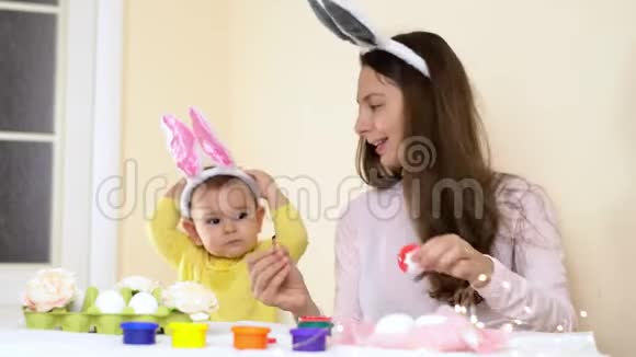 复活节快乐的家庭妈妈和宝宝在家里画鸡蛋有兔子耳朵的季节性传统视频的预览图