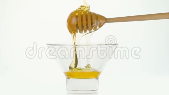 玻璃碗倒入蜂蜜和木棍蘸白色背景视频的预览图
