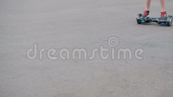 这个少年骑在沥青上的一个自平衡的两轮气垫板上从右上角移动到底部l视频的预览图