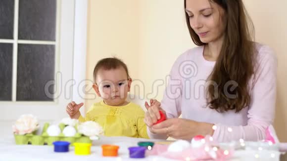 复活节快乐的家庭妈妈和宝宝在家里画鸡蛋有兔子耳朵的季节性传统视频的预览图