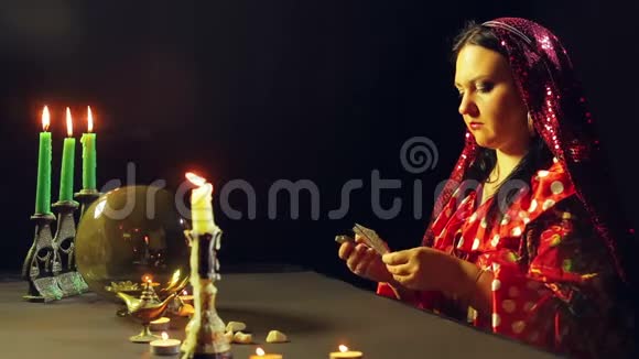 一个年轻的吉普赛人穿着红色的裙子在烛光下的桌子上读到了未来平均计划视频的预览图
