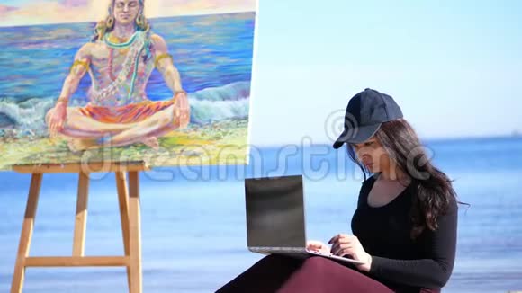 夏天海边日出美丽的女艺术家在业余时间画画在笔记本电脑上工作在社交中交流视频的预览图