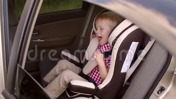 一个快乐的笑男孩在汽车座椅上的肖像视频的预览图