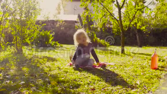 小女孩坐在花园的草地上穿上鞋子视频的预览图