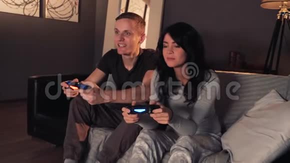 两个人在游戏机上玩视频游戏坐在家里的沙发上女孩赢了视频的预览图