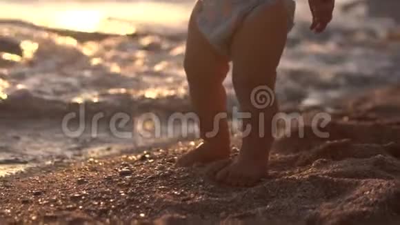 可爱的特写镜头的婴儿腿使台阶在沙滩上视频的预览图