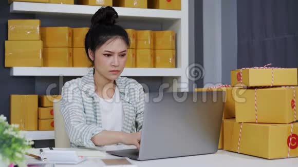 穿着衣服的女人用她的笔记本电脑和快递包裹盒工作视频的预览图