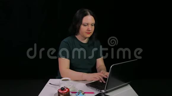 咖啡馆的一个黑发女孩在电脑前工作在咖啡馆喝咖啡视频的预览图