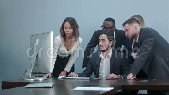 一群多种族的商人围着会议桌看着笔记本电脑互相交谈视频的预览图