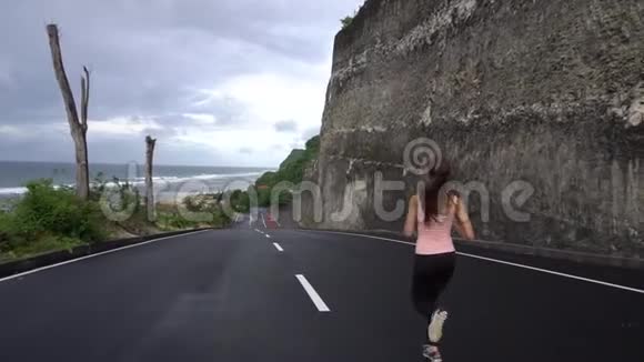 阳光明媚的一天女孩在悬崖边的岩石路上奔跑视频的预览图