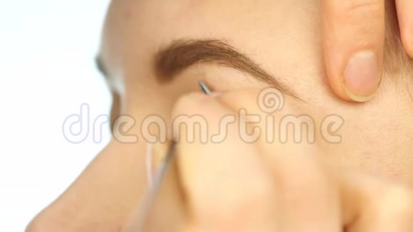 特写化妆师的手用画笔将眼影涂在女人眼睛上4K视频的预览图