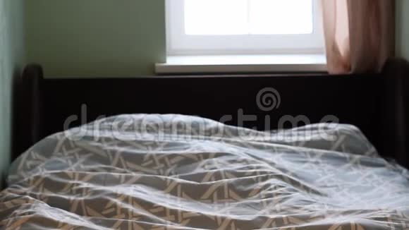 一个年轻的女孩躺在床上清晨醒来啜饮着她的双手视频的预览图